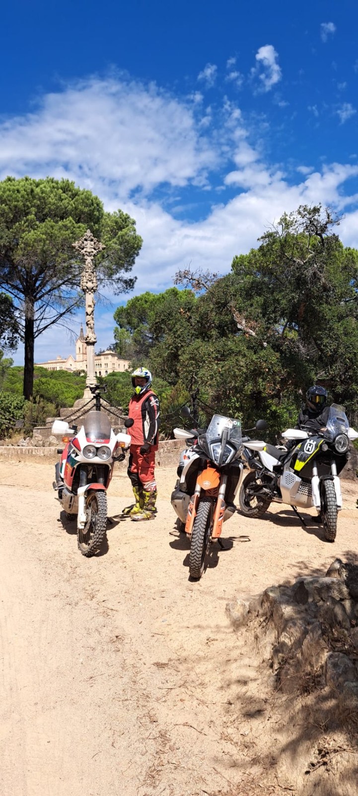 Pilotos con sus motos en una pista soleada entre pinos